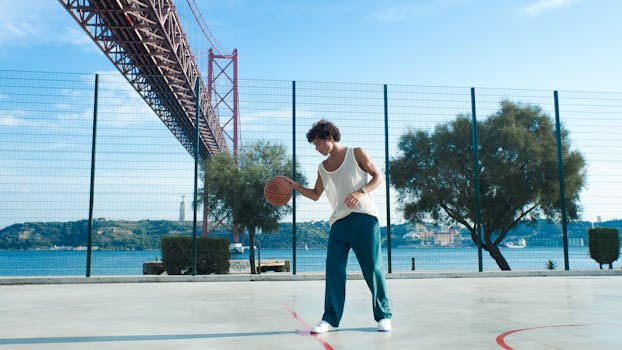 A man dribbles a basketball on an outdoor court near Lisbon's 25 de Abril Bridge.